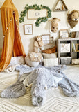 A large plush elephant rug made by ClaraLoo on the floor of a safari themed nursery. The elephant rug features soft gray faux fur with a crocheted snout and tusks.
